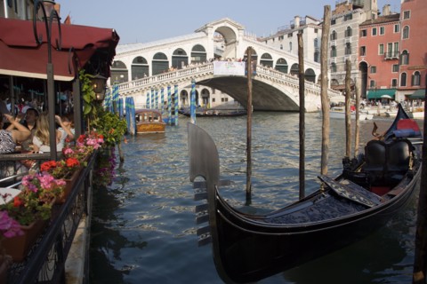 ITALY, Veneto, Venice, A gondola moored beside a restaurant on the Grand Canal with tourists dining