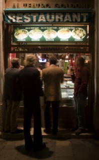 ITALY, Veneto, Venice, Men standing and eating at the street window of a restaurant near the