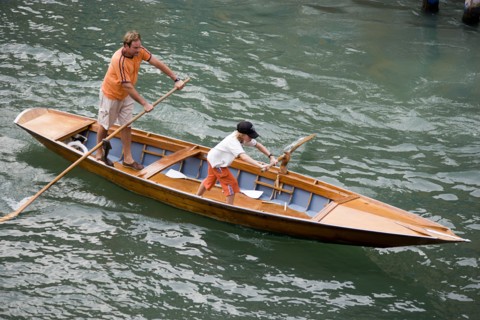 ITALY, Veneto, Venice, Man and young boy rowing a traditional boat in the gondola manner along the
