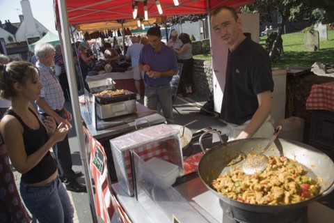 ENGLAND, West Sussex, Shoreham-by-Sea, French Market. Stallholder cooking chicken and vegetable