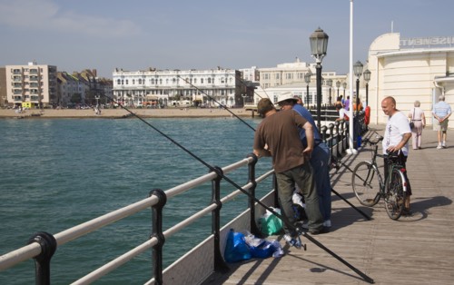 ENGLAND, West Sussex, Worthing, Men fishing off the pier