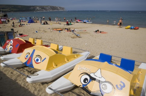 ENGLAND, Dorset, Swanage Bay, Colourful pedalo leisure boats painted with faces on sandy beach