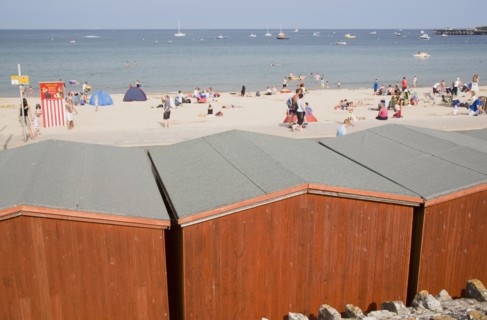 ENGLAND, Dorset, Swanage Bay, View across beach hut roofs towards busy sandy beach and sea