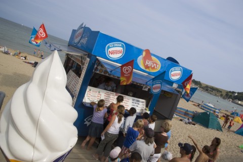 ENGLAND, Dorset, Swanage Bay, A group of children queuing at an Ice Cream stall. Angled view with a