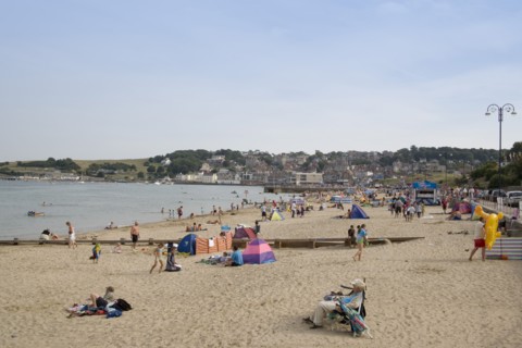 ENGLAND, Dorset, Swanage Bay, View along sandy beach with sunbathers on the sand
