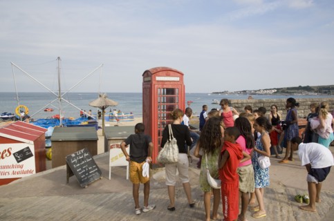 ENGLAND, Dorset, Swanage Bay, A group of children gathered near a traditional red phone box
