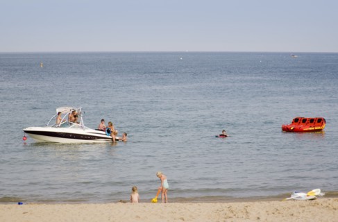ENGLAND, Dorset, Swanage Bay, Children playing at the waters edge of a sandy beach with people on a