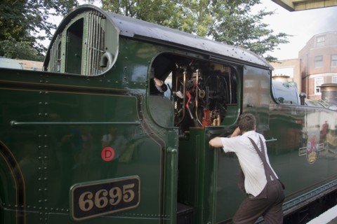 ENGLAND, Dorset, Swanage , Steam Railway. Train driver leaning against train engine waiting in