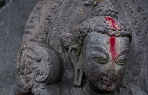 NEPAL, Kathmandu, Detail of Buddha statue anointed with pink powder.