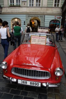 CZECH REPUBLIC, Bohemia, Prague, "Tourists walking past a red Skoda, parked in the street, used for