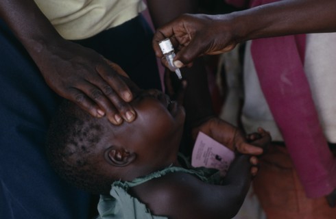 UGANDA, Medical, Health worker administering immunization polio drops to child in area near Gulu.