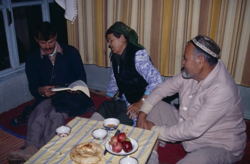 UZBEKISTAN, Tashkent, "Uzbek family sat around tablke, with one man reading a book."
