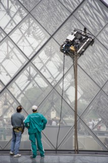 FRANCE, Ile de France, Paris, Workmen watching robot window cleaning machine on the pyramid at the