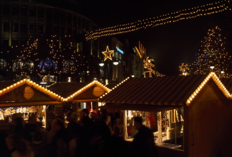 GERMANY, Berlin, Breitscheidplatz. Christmas Market. People gathered around Illuminated stalls at