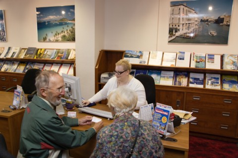 ENGLAND, West Sussex, Chichester, Male and female customer in a Travel Agents office discussing