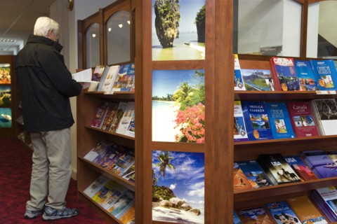 ENGLAND, West Sussex, Chichester, Male customer in a Travel Agents office looking through travel