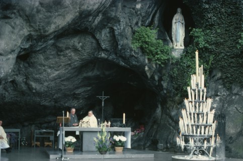 FRANCE, Midi-Pyrenees, Hautes-Pyrenees, Lourdes.  Priest conducting service at cave shrine in