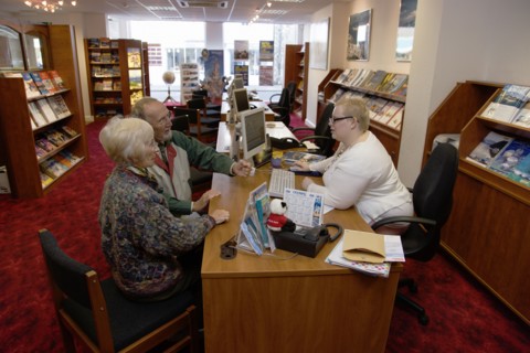 ENGLAND, West Sussex, Chichester, Male and female customer in a Travel Agents office discussing