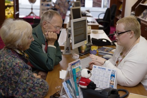 ENGLAND, West Sussex, Chichester, Male and female customer in a Travel Agents office discussing