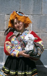 PERU, Cusco, "Lady wearing a colourful costume holding a lamb in her arms,"
