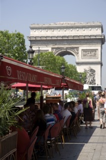 FRANCE, Ile de France, Paris, Tourists eating lunch at tables under shade in the Champs Elysees