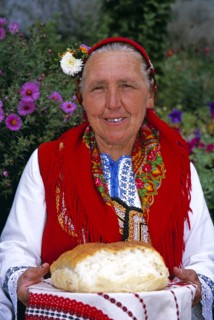 BULGARIA, Dobarsko, "Dobarski Babi Folk Group, member of folk group holding bread on plate."