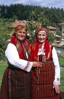 BULGARIA, Dobarsko, "Member of Dobarski Babi Folk Group, and tourist on right, in national costume"