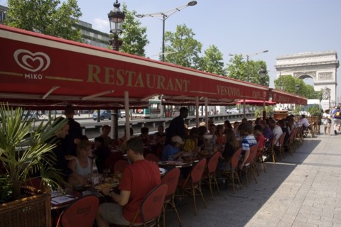FRANCE, Ile de France, Paris, Tourists eating lunch at tables under shade in the Champs Elysees
