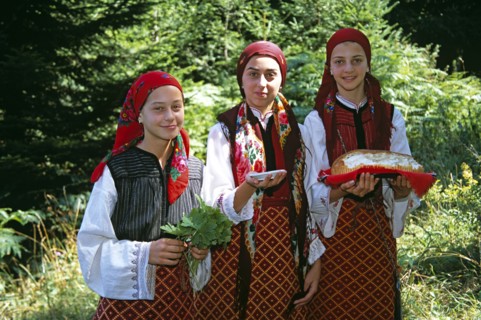 BULGARIA, Pirin Mountain, Chalin Valog, "Girls dressed in Bulgarian national costume holding bread,