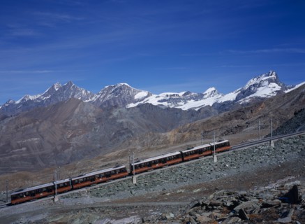SWITZERLAND, Valais, Zermatt, "Gornegrat Railway with train traveling past snow capped mountains
