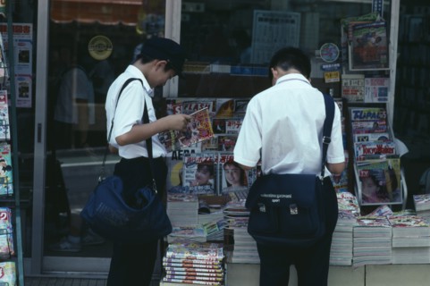 JAPAN, Chiba, Narita, Two Junior High Japanese schoolboys in uniform reading magazines from