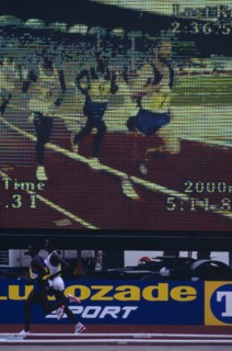 20085195 SPORT Athletics Running Male athletes at a meeting running past an electronic viewing screen