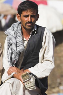 AFGHANISTAN, Kabul, Money changer sits on rug on walls of Kabul river