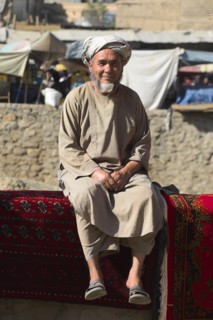 AFGHANISTAN, Kabul, Rug seller sit on walls of Kabul river