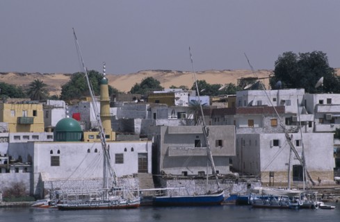 EGYPT, Near Aswan, Elephantine Island, Nile River Nubian Village with boats moored on water next to