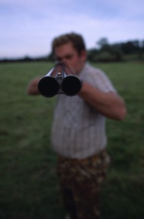 20085231 SPORT Shooting Guns Man holding double barrelled shotgun with detail of the tip of the gun in focus.