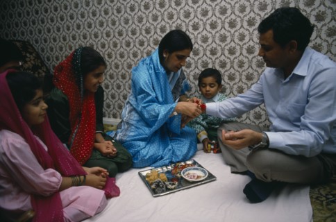 ENGLAND, Religion, Hindu, Woman tying thread on wrist of man during the Sacred Thread ceremony. The