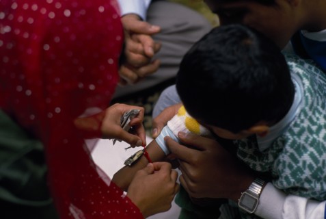 ENGLAND, Religion, Woman tying thread on arm of boy during the Sacred Thread ceremony. The Hindu