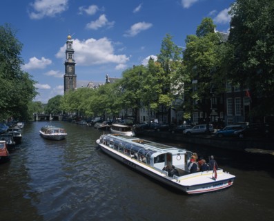 HOLLAND, Noord-Holland, Amsterdam, Pleasure boats on canal lined by trees and parked cars on side