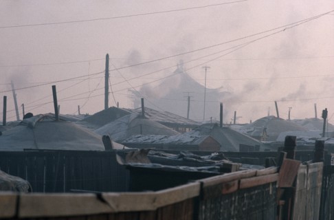 MONGOLIA, Ulan Bator, Yurt district with shadowy grey rooftop of the Gandan Monastery behind in