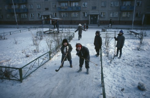 MONGOLIA, Ulan Bator, Children playing ice hockey along pavements in winter snow.