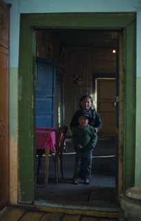 MONGOLIA, North, Children, Brother and sister standing in open doorway of home with green painted