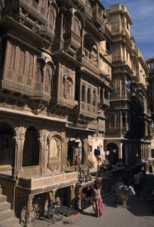 INDIA, Rajasthan, Jaisalmer, Patwon ki Haveli exterior with people and cattle seen on the path at