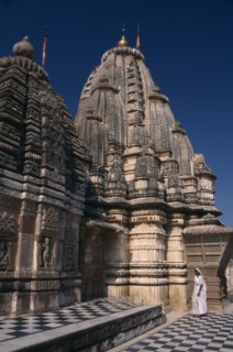 INDIA, Rajasthan, Osian, Sachiya Mata Temple with a woman dressed in white standing at the base