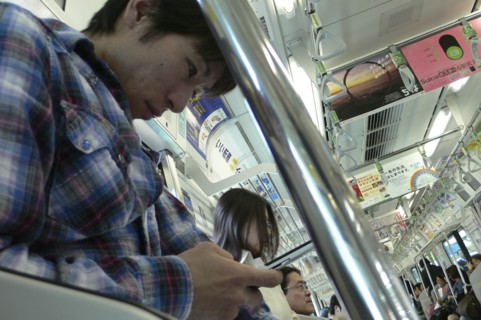 JAPAN, Honshu, Tokyo, "JR train, a young man uses his cell phone, text message"