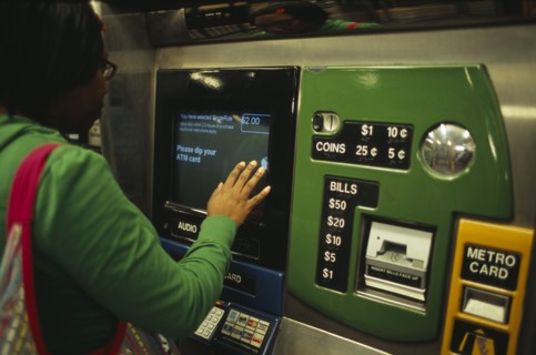 USA, New York, New York City, Young woman using metro ticket machine to purchase ticket.