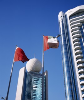 UAE, Dubai, Deira, Etisalat Building on Dubai Creek with flag poles in foreground.
