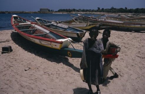 SENEGAL, Fishing, Two children on beach beside line of painted fishing boats pulled up onto the