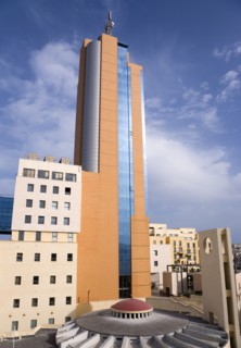 MALTA, Saint Julians, Portomaso Hilton Tower office complex towering above a small church with dome
