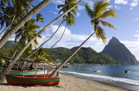 WEST INDIES, St Lucia, Soufriere, Fishing boats on the beach lined with coconut palm trees with the